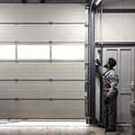 Full length of serviceman opening garage door at auto mechanic workshop