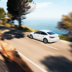 A white 2022 Civic Sedan driving along a beach or ocean road