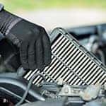 A car service worker is holding in hands old car air filter close up.