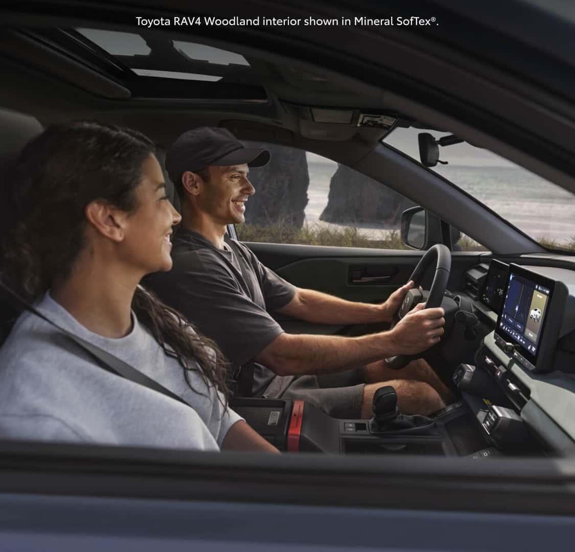 Side interior view through the open window of a 2026 Toyota RAV4 Woodland Edition in Mineral SofTex®.
