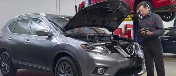A person standing by a car with the hood open