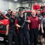 Group of people posing in front of a red truck
