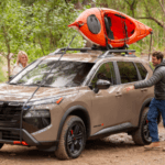 A person getting in a car with a kayak on top