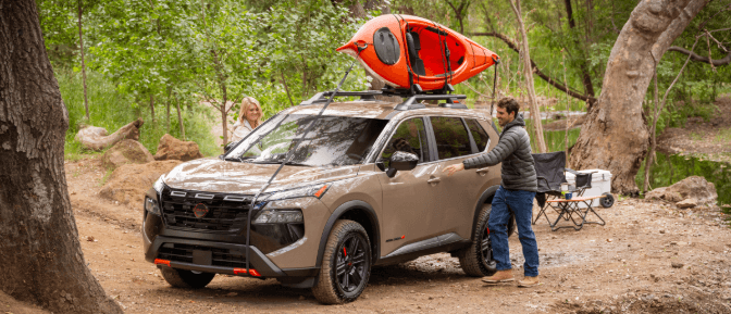 A person getting in a car with a kayak on top
