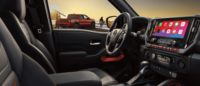 A car with a steering wheel and a red truck in the background