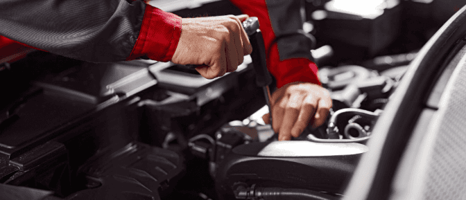 A close-up of a mechanic working on a car engine