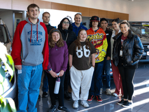 Group of students and adults from Mt. Spokane High School touring a Nissan dealership showroom.