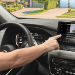 A driver using the NissanConnect touchscreen inside a vehicle to operate a garage door via the myQ Garage interface.