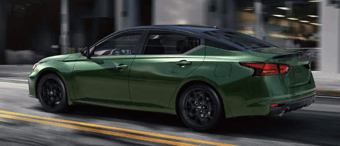 Side profile of a metallic green Nissan Altima SR driving on a city street.