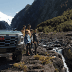 2026 Nissan Armada parked near mountains with five people. Family adventure SUV in a rugged outdoor setting.