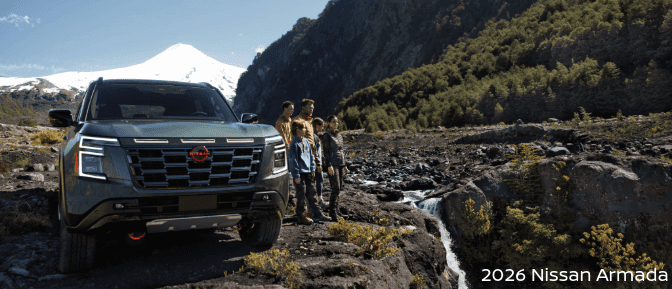 2026 Nissan Armada parked near mountains with five people. Family adventure SUV in a rugged outdoor setting.