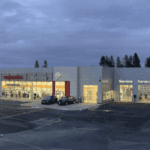 Wide view of the Wendle Nissan dealership in Spokane at dusk, showing the lit showroom, service bays and parking lot.