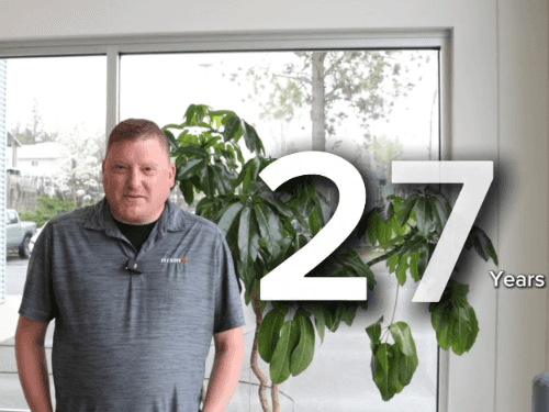 A dealership employee standing in a showroom with a large graphic overlay celebrating his 27 years of service.