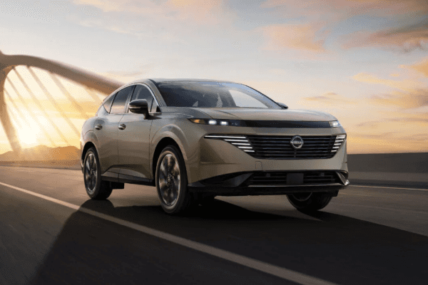 Champagne gold Nissan Murano driving across a bridge during sunset.