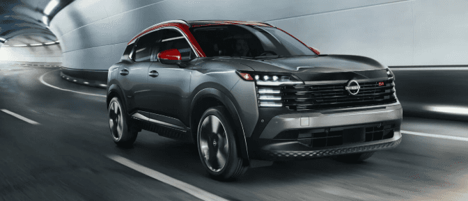 Two-tone gray and red Nissan Kicks SR crossover driving inside a modern futuristic roadway tunnel.