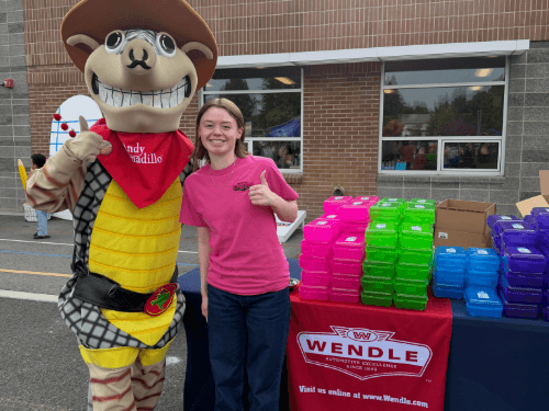 Wendle representative giving a thumbs-up next to the Andy Armadillo mascot at a Shiloh Hills community event.