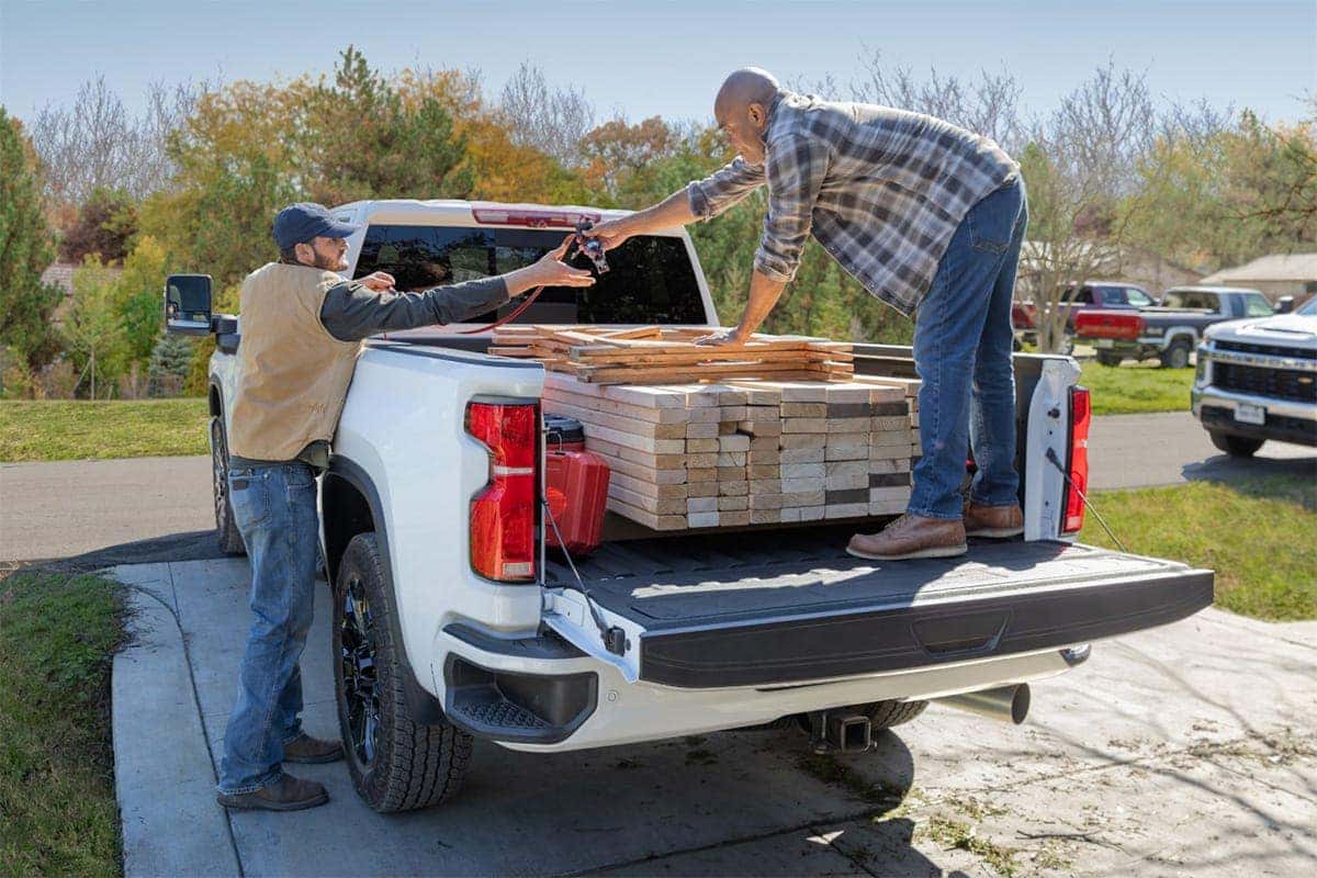 people loading a silverado with lumber 