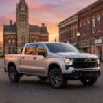 Silver Chevrolet Silverado truck driving past Marshfield’s Old City Hall during an evening golden hour scene