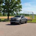 Chevrolet Silverado parked in a rural Wisconsin baseball park parking lot with oak trees, benches, and a small-town baseball field in the background