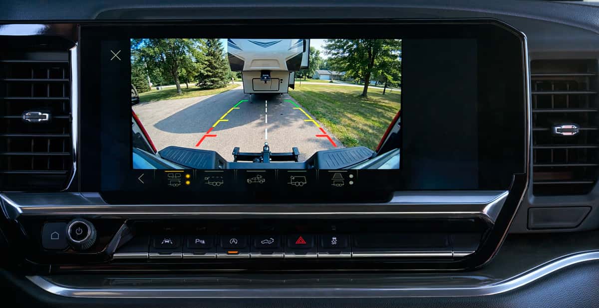 Rear backup camera view inside a 2026 Chevrolet Silverado showing fifth wheel camper alignment with dynamic parking guidelines on a Wisconsin driveway