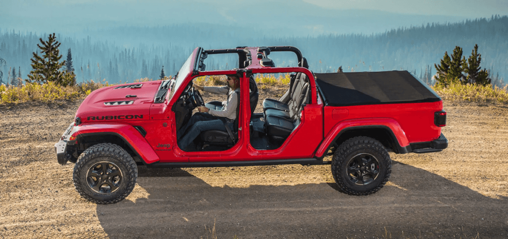 A red 2023 Jeep Gladiator driving along forested road